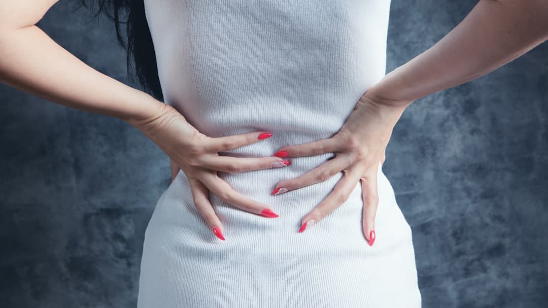 腰痛で腰に手を当てがう女性